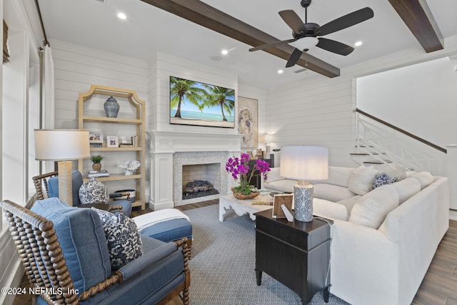 living room featuring beamed ceiling, hardwood / wood-style floors, wood walls, and ceiling fan