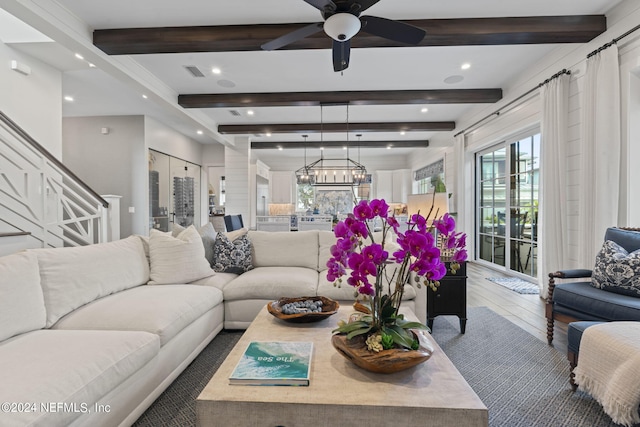 living room with ceiling fan with notable chandelier, dark wood-type flooring, and beamed ceiling