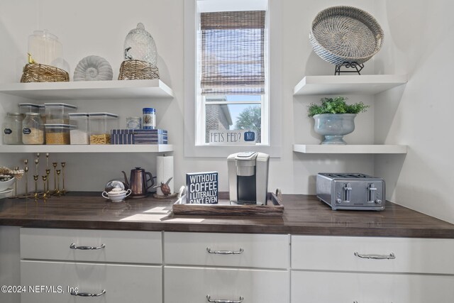 bar featuring butcher block countertops and white cabinets