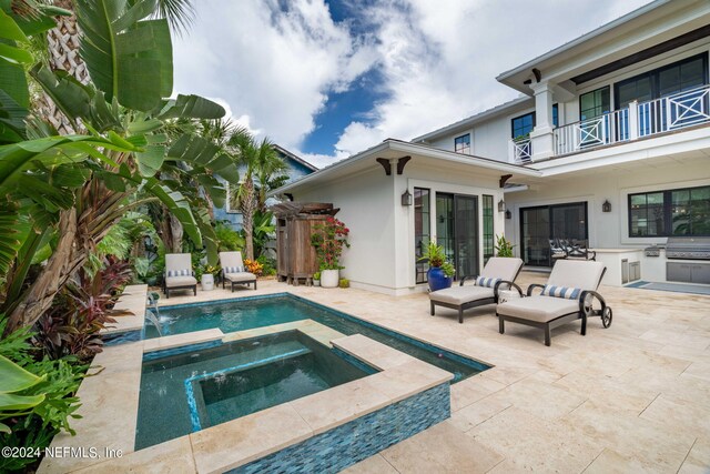 view of pool featuring an in ground hot tub, pool water feature, a grill, and a patio area