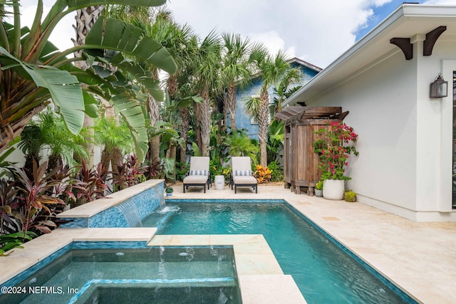 view of pool featuring an in ground hot tub, pool water feature, and a patio