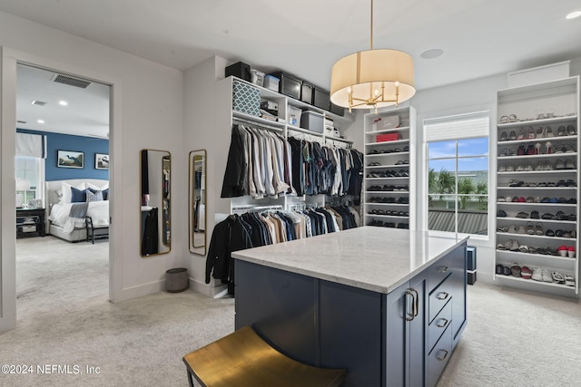 walk in closet featuring a chandelier and light colored carpet