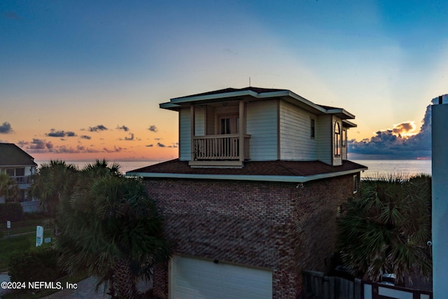 property exterior at dusk with a garage and a water view