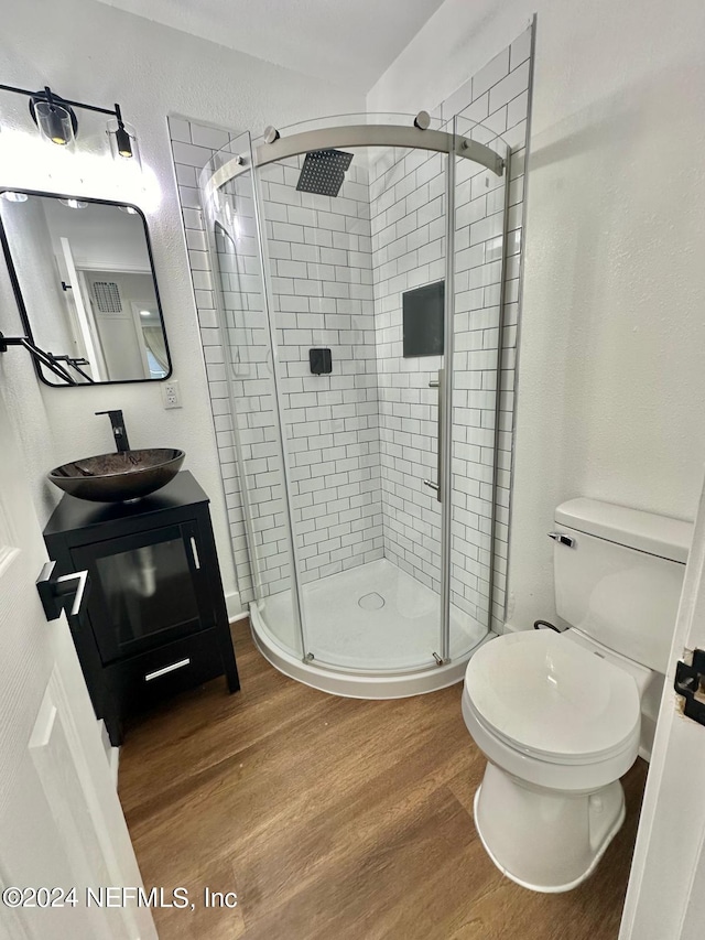 bathroom featuring hardwood / wood-style floors, vanity, toilet, and a shower with shower door