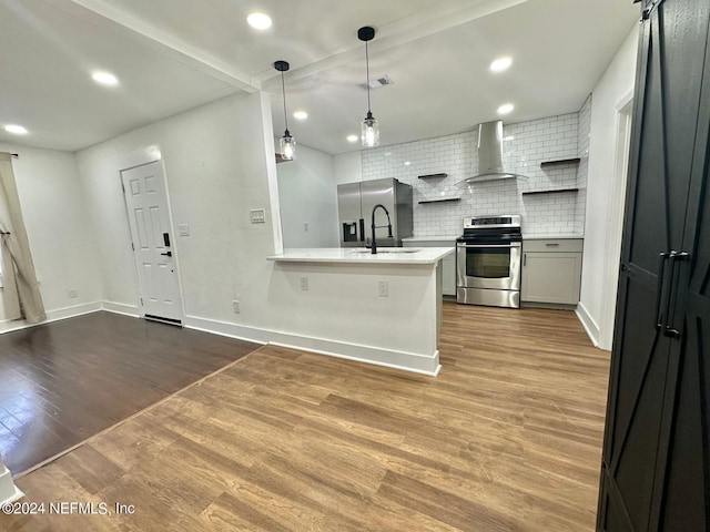 kitchen with sink, hanging light fixtures, hardwood / wood-style flooring, wall chimney exhaust hood, and stainless steel appliances