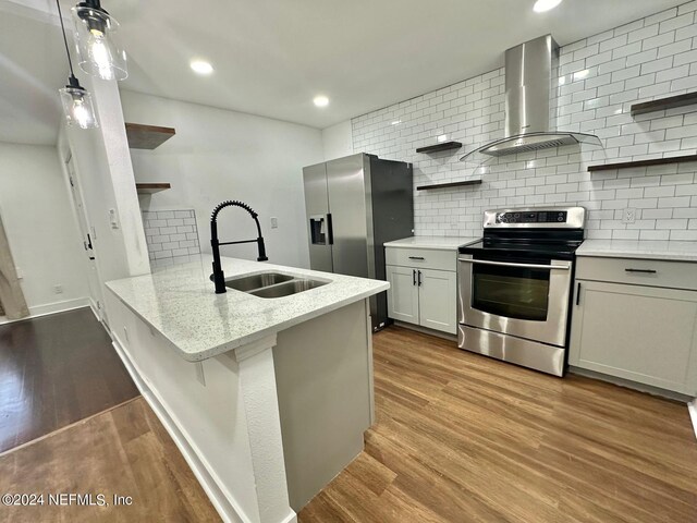 kitchen featuring hardwood / wood-style floors, wall chimney exhaust hood, kitchen peninsula, and stainless steel appliances