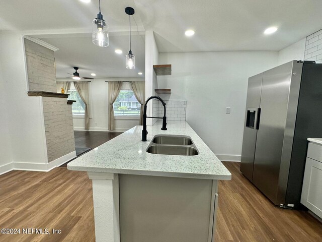 kitchen with stainless steel fridge with ice dispenser, light stone counters, hanging light fixtures, and dark wood-type flooring