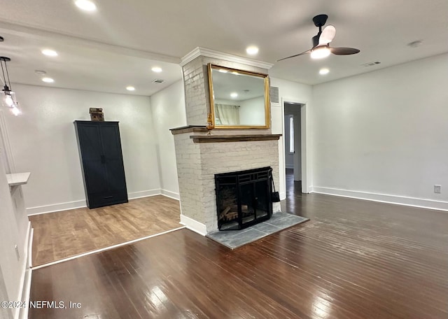 unfurnished living room featuring a stone fireplace, ceiling fan, and dark wood-type flooring