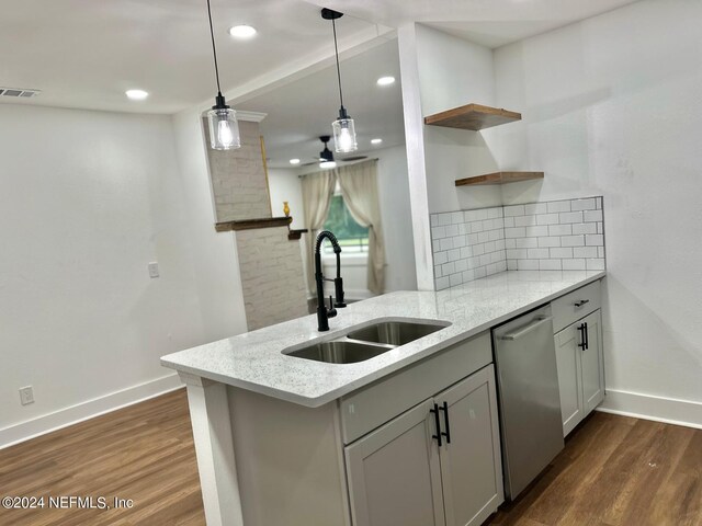 kitchen featuring light stone countertops, kitchen peninsula, stainless steel dishwasher, sink, and dark hardwood / wood-style floors