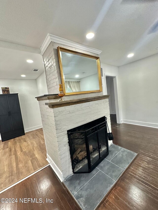 room details with hardwood / wood-style floors, a textured ceiling, and a brick fireplace