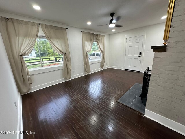 unfurnished living room with ceiling fan and dark wood-type flooring