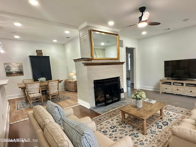 living room with hardwood / wood-style floors, ceiling fan, and a fireplace