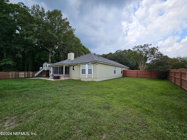 back of house with a sunroom and a lawn