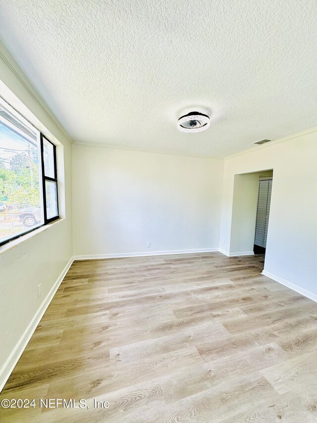 spare room featuring light hardwood / wood-style flooring and a textured ceiling