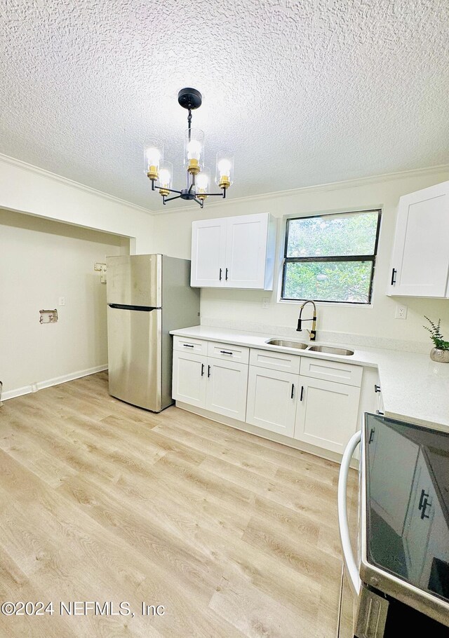 kitchen with sink, stainless steel fridge, decorative light fixtures, light wood-type flooring, and white cabinets