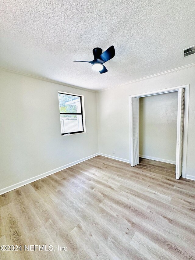 spare room featuring a textured ceiling, light wood-type flooring, and ceiling fan