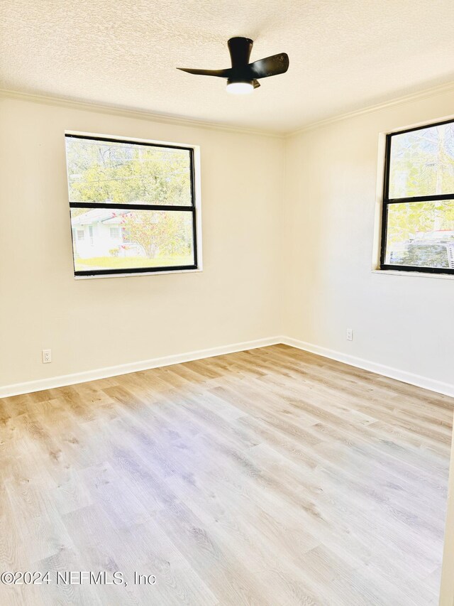 spare room featuring light hardwood / wood-style flooring, a textured ceiling, ceiling fan, and a wealth of natural light