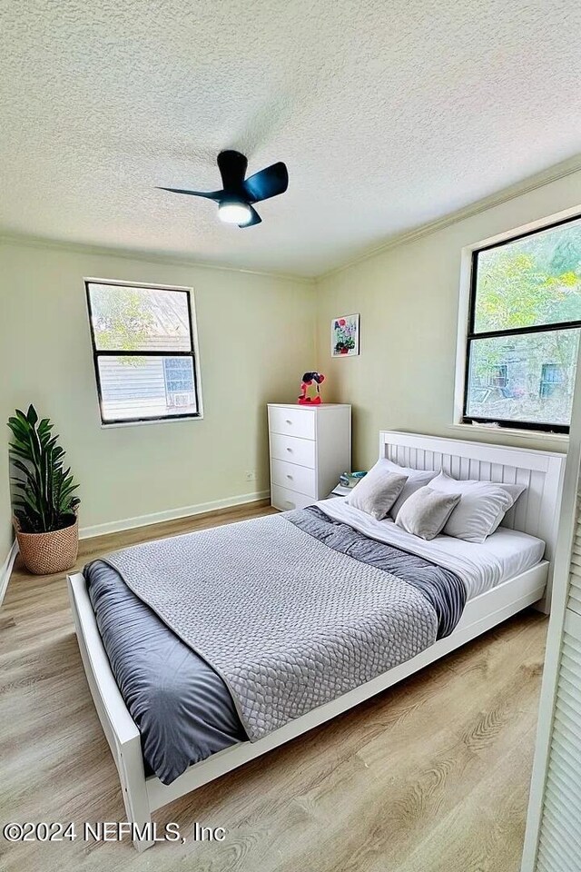 bedroom with light hardwood / wood-style floors, a textured ceiling, and ceiling fan