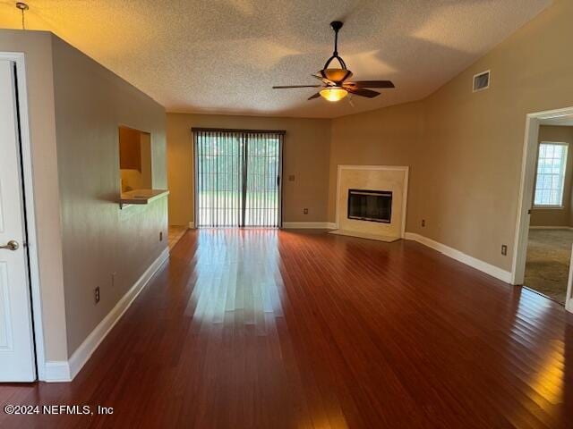 unfurnished living room featuring lofted ceiling, plenty of natural light, ceiling fan, and dark hardwood / wood-style floors