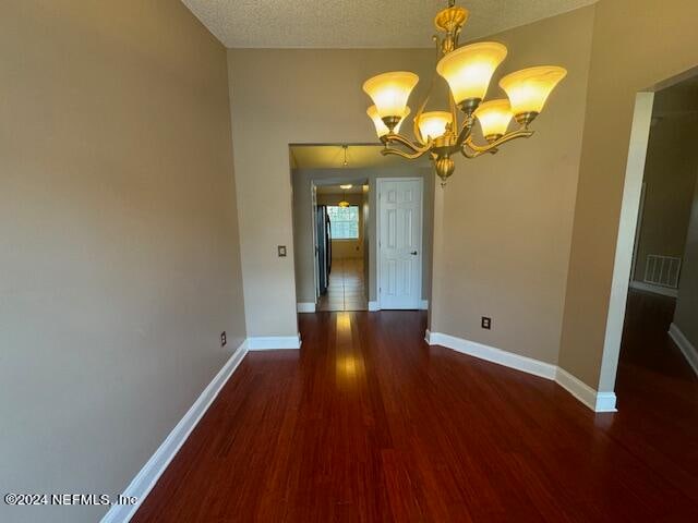 unfurnished dining area with dark hardwood / wood-style floors, a notable chandelier, and a textured ceiling