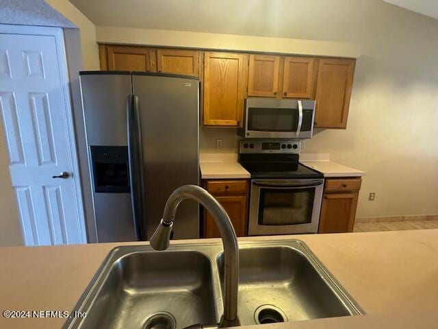 kitchen with lofted ceiling, stainless steel appliances, and sink