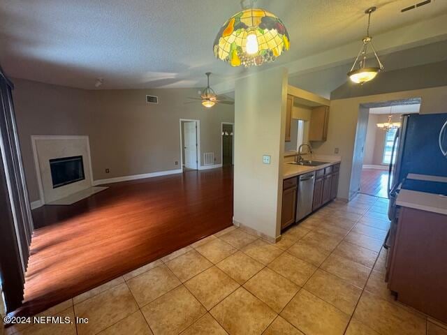 kitchen with ceiling fan with notable chandelier, a fireplace, light hardwood / wood-style flooring, appliances with stainless steel finishes, and sink