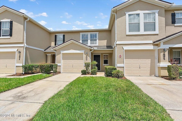 view of property featuring a garage, a front yard, concrete driveway, and stucco siding