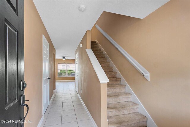 stairs with tile patterned flooring and ceiling fan