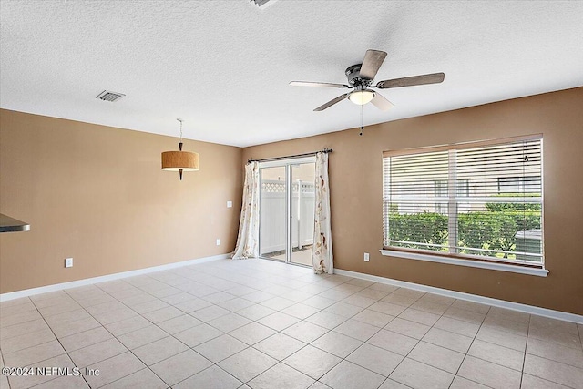 tiled empty room featuring ceiling fan and a textured ceiling