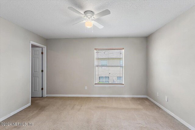 unfurnished room featuring a textured ceiling, ceiling fan, and light carpet