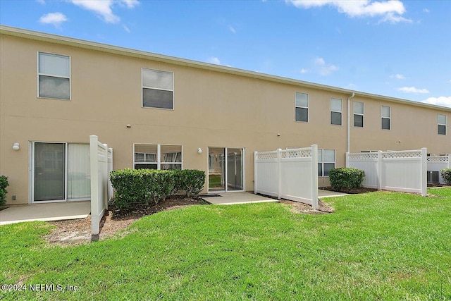 back of property featuring a yard, fence, and stucco siding