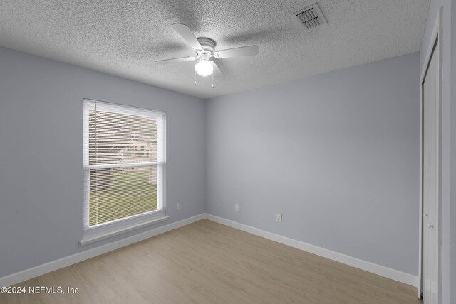 spare room with ceiling fan, light hardwood / wood-style flooring, and a textured ceiling