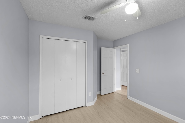 unfurnished bedroom with ceiling fan, light wood-type flooring, a textured ceiling, and a closet