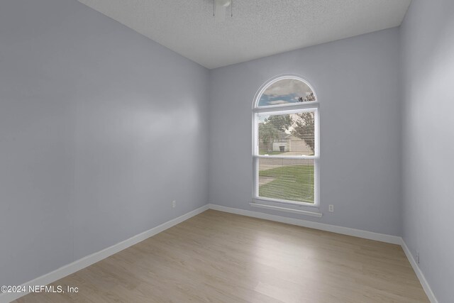 unfurnished room with a textured ceiling and light wood-type flooring