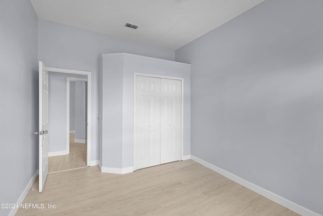 unfurnished bedroom featuring a closet, light wood-type flooring, visible vents, and baseboards