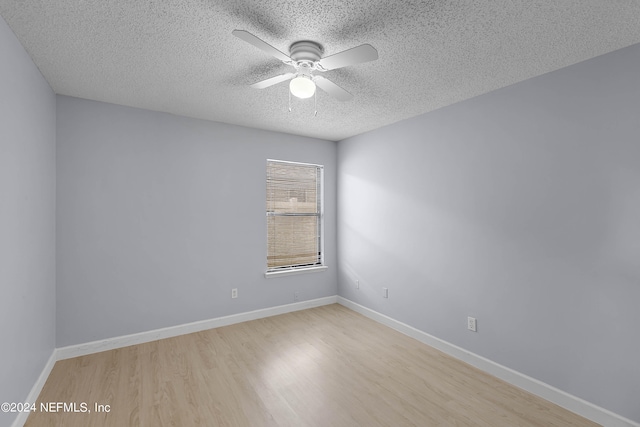 empty room with ceiling fan, light wood-type flooring, and a textured ceiling