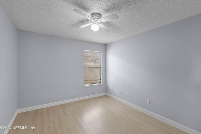 empty room with light wood-type flooring, a textured ceiling, baseboards, and a ceiling fan