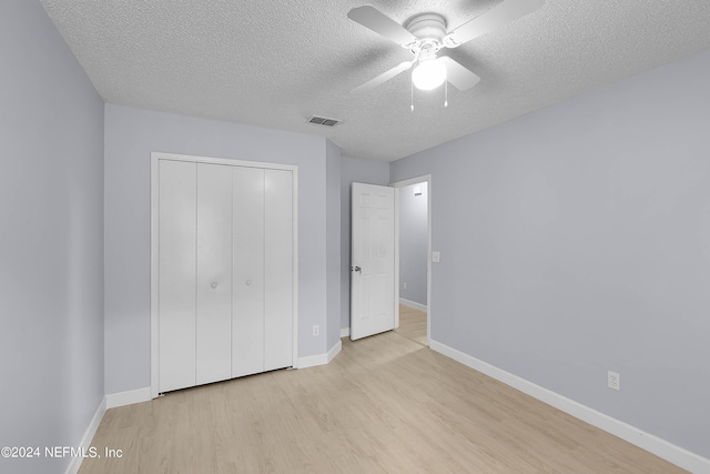 unfurnished bedroom with a closet, visible vents, light wood-style flooring, a textured ceiling, and baseboards