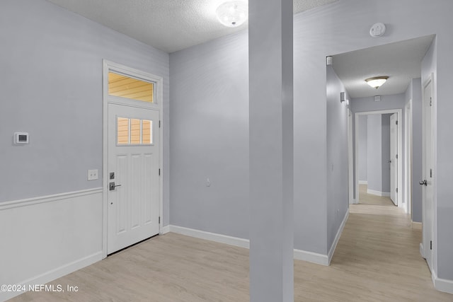 entrance foyer featuring a textured ceiling, light wood finished floors, and baseboards