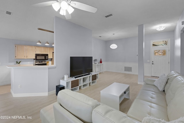 living room with ceiling fan, light wood-type flooring, and a high ceiling