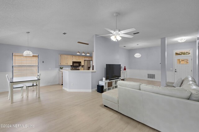 living room with a textured ceiling, light hardwood / wood-style floors, and ceiling fan