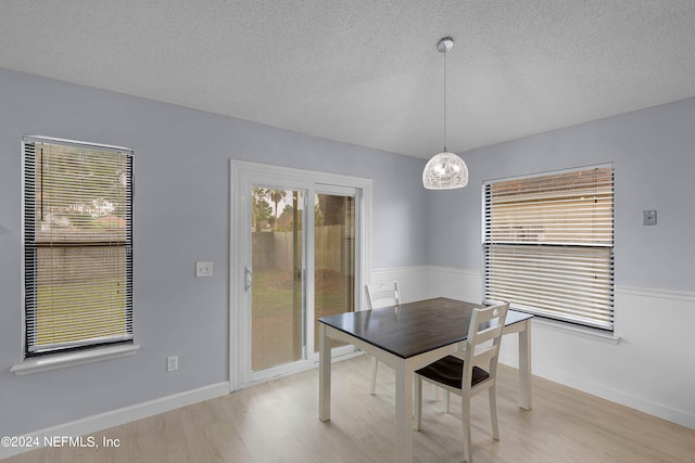 unfurnished dining area featuring a textured ceiling and light hardwood / wood-style flooring