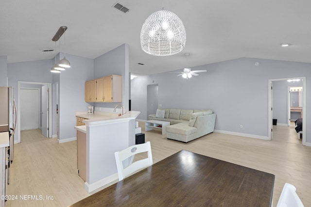 kitchen with stainless steel refrigerator, light brown cabinets, kitchen peninsula, ceiling fan with notable chandelier, and light wood-type flooring