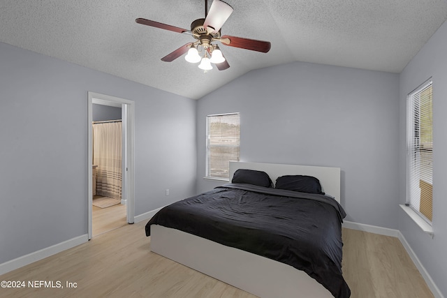 bedroom with connected bathroom, light hardwood / wood-style floors, vaulted ceiling, and ceiling fan