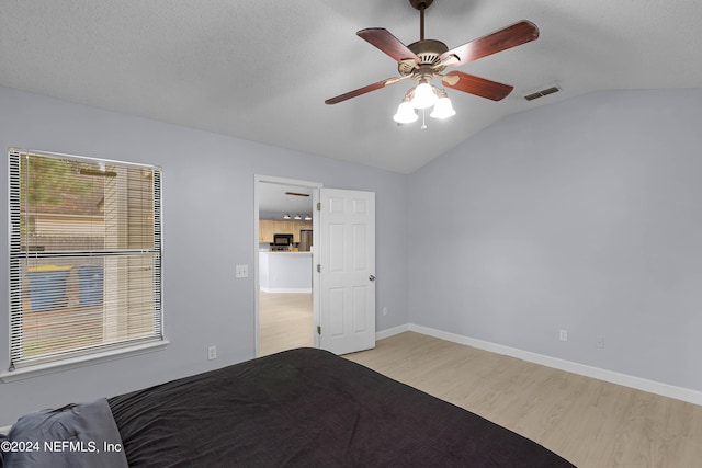 unfurnished bedroom with light wood finished floors, visible vents, vaulted ceiling, ceiling fan, and baseboards