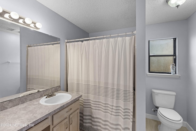 bathroom with vanity, a textured ceiling, and toilet