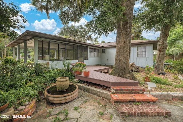 rear view of property with a sunroom and a deck