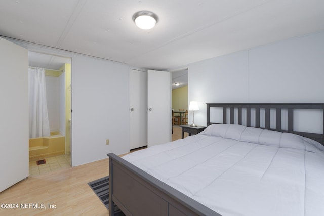 bedroom featuring ensuite bath and light hardwood / wood-style floors