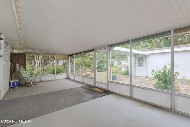 unfurnished sunroom featuring vaulted ceiling and plenty of natural light