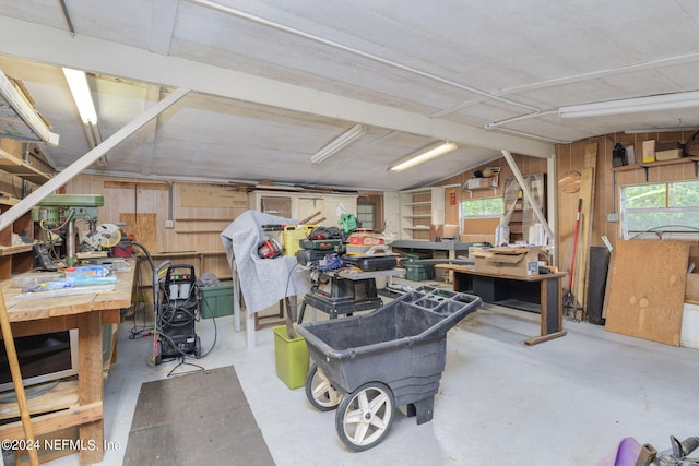 misc room featuring plenty of natural light, concrete floors, wood walls, and a workshop area